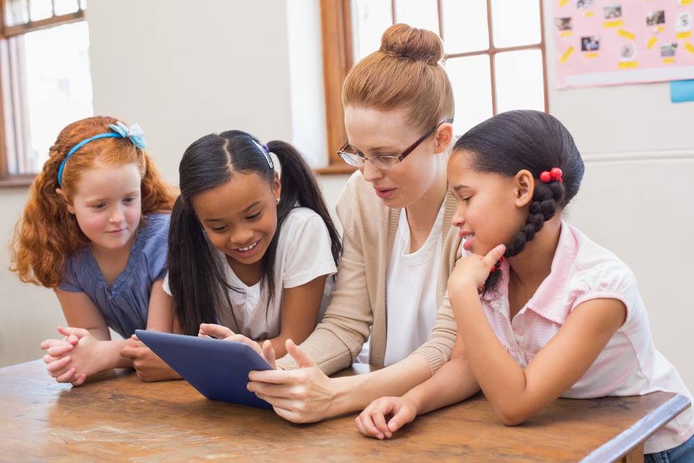 Teacher and pupils looking at tablet computer at the elementary school